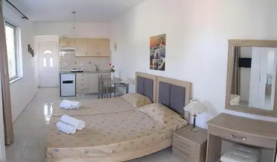 a bedroom with a large bed and a kitchen at Artemis Studios - Pool and garden in Koskinou