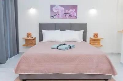 a bed with a pink blanket and white pillows at AS ALESIAS SUITES.Room 12. in Rhodes Town