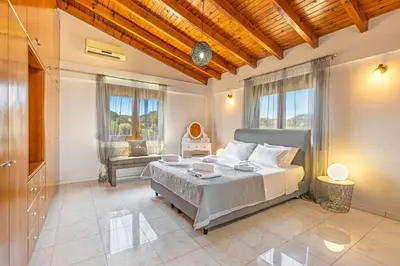 a bedroom with a large bed in a room with windows at Prestige Residence Rhodes in Ialyssos