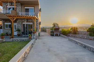 a pathway leading to a house with the sunset in the background at Electi Apartments Charaki in Haraki