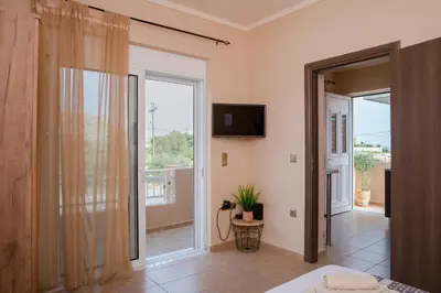a bedroom with a room with a television and a balcony at Electi Apartments Charaki in Haraki