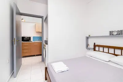 a small bedroom with a bed and a kitchen at Studio Amarantios in Rhodes Town