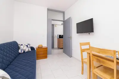 a living room with a blue couch and a tv at Studio Amarantios in Rhodes Town