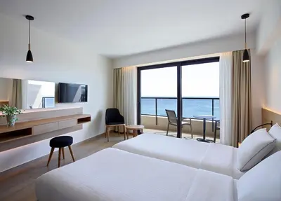 a hotel room with a bed and a view of the ocean at Cactus Hotel in Rhodes Town