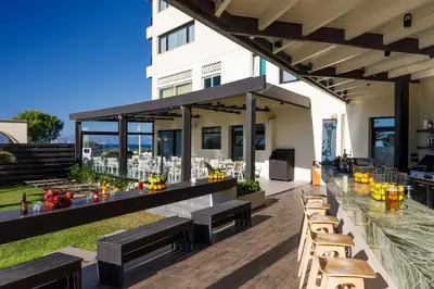 an outdoor patio with wooden benches and tables at Cactus Hotel in Rhodes Town