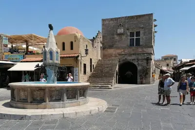 a group of people standing around a fountain in a street at Natasha's Nest in Rhodes Town