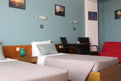 a hotel room with two beds and a red chair at Planet View in Faliraki