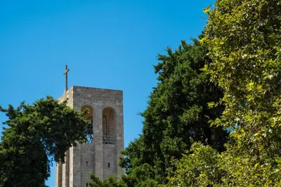 a tower with a cross on top of it with trees at La Casa di Efi in Rhodes Town