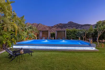 a large blue swimming pool in a yard with a table at Gaia Blue Villa in Kolimbia
