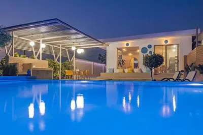 a swimming pool in front of a house at night at Gaia Blue Villa in Kolimbia