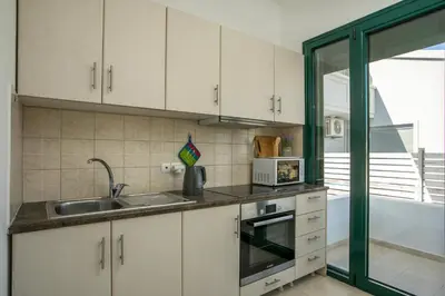a kitchen with white cabinets and a sink and a tub at Kelly's Beach House 1 in Gennadi