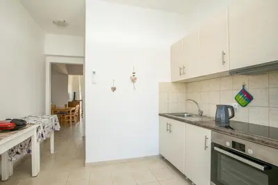 a kitchen with white cabinets and a sink and a table at Kelly's Beach House 1 in Gennadi