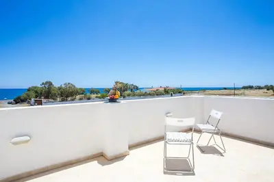 a balcony with two chairs and a view of the ocean at Kelly's Beach House 1 in Gennadi