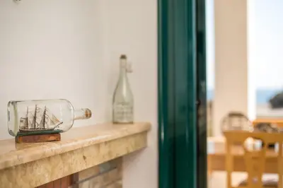 a glass jar with a ship in it sitting on a mantle at Kelly's Beach House 1 in Gennadi