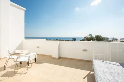 a bedroom with a balcony with a view of the ocean at Kelly's Beach House 1 in Gennadi