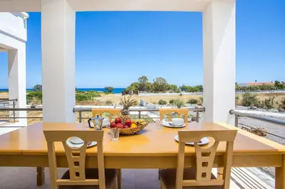 a dining room with a table and chairs and a view of the ocean at Kelly's Beach House 1 in Gennadi