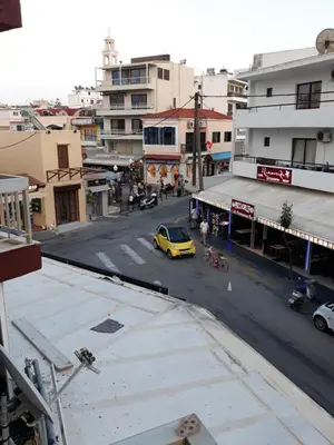 a yellow car driving down a city street with buildings at AS SUITES ROOM 14 in Rhodes Town