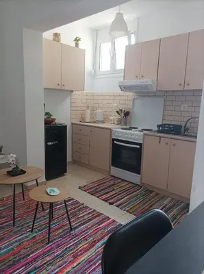a kitchen with white cabinets and a stove and a table at Sable Blanc Apartments in Ixia