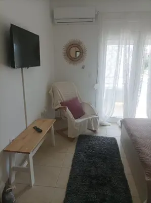 a living room with a bed and a tv and a chair at Sable Blanc Apartments in Ixia