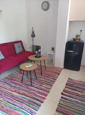 a living room with a red couch and two tables at Sable Blanc Apartments in Ixia