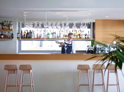 a man standing behind a bar with bar stools at Aquarium View Hotel in Rhodes Town