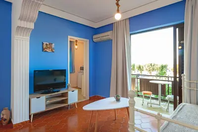 a living room with blue walls and a television at CHAMBRE BLEUE in Ialyssos
