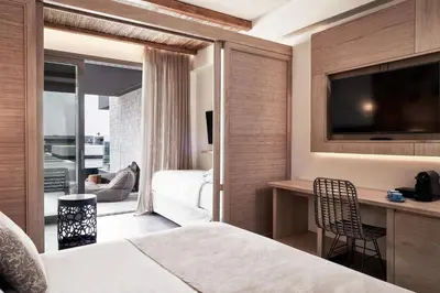 a hotel room with a bed and a desk and a television at Atlantica Dreams Resort in Gennadi