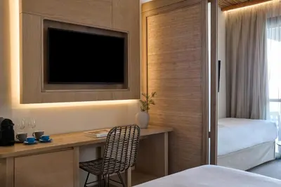 a bedroom with a desk with a tv and a bed at Atlantica Dreams Resort in Gennadi