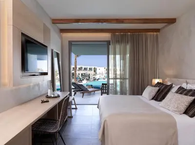 a hotel room with a bed and a desk and a balcony at Atlantica Dreams Resort in Gennadi