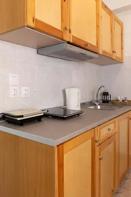 a kitchen with wooden cabinets and a counter top at Kampus Living Luxury Complex in Faliraki