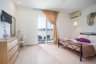 a bedroom with a bed and a tv and a window at Kampus Living Luxury Complex in Faliraki