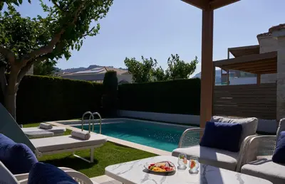 a backyard with a swimming pool with chairs and a table at Atlantica Holiday Village Rhodes in Kolimbia
