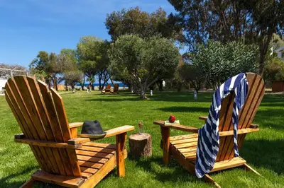 two wooden chairs sitting on the grass in a park at Eco Beach And Magic Garden Hotel in Gennadi