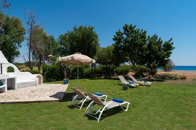 a group of chairs and an umbrella on the grass at Eco Beach And Magic Garden Hotel in Gennadi