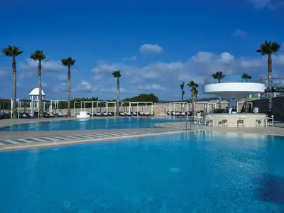 a large swimming pool with palm trees in the background at Atlantica Plimmiri in Plimmiri