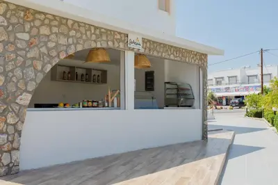 a restaurant with a white counter and a stone wall at Belmare Hotel in Lardos