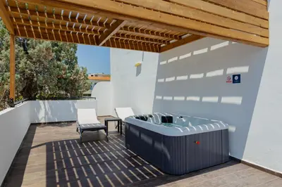 a deck with a hot tub and a table and chairs at Belmare Hotel in Lardos