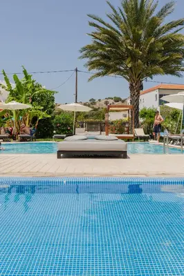 a pool at a resort with a palm tree at Belmare Hotel in Lardos