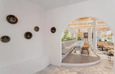 a dining room with an archway and tables and chairs at Belmare Hotel in Lardos