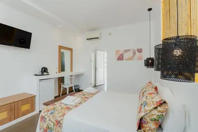 a white bedroom with a bed and a tv at Belmare Hotel in Lardos