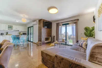a living room with a couch and a kitchen at Heliophos Villa Amalthia in Kiotari