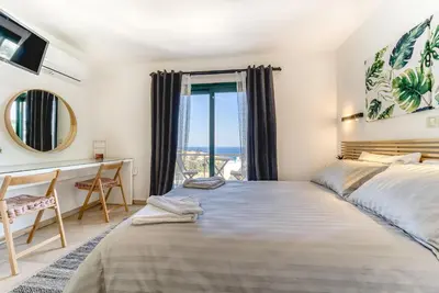 a bedroom with a bed and a desk and a window at Heliophos Villa Amalthia in Kiotari