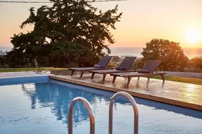 a pool with two lounge chairs next to the ocean at Luxury Rhodes Villa Anissa Villa Sea View Private Swimming Pool in Rhodes Town