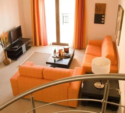 a living room with an orange couch and a tv at Executive Rhodes Villa 4 Bedroom 4 Bathroom Bd Villa Pefkos in Pefki Rhodes