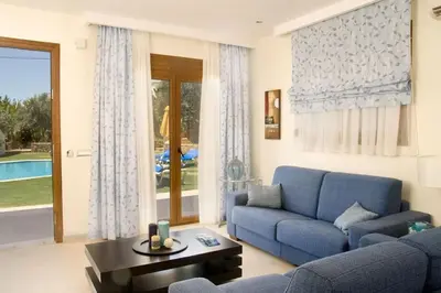 a living room with a blue couch and a table at Executive Rhodes Villa 4 Bedroom 4 Bathroom Bd Villa Pefkos in Pefki Rhodes