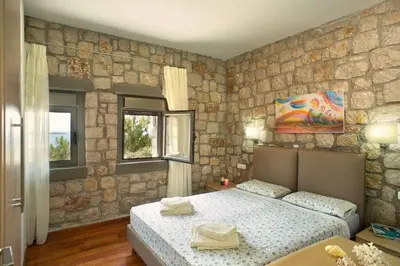 a bedroom with a bed and a stone wall at Executive Rhodes Villa Villa Ellie 2 Bedroom Villa With Sea Views Pefkos in Pefki Rhodes