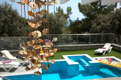 a group of shells hanging from a chain next to a swimming pool at Executive Rhodes Villa Villa Ellie 2 Bedroom Villa With Sea Views Pefkos in Pefki Rhodes
