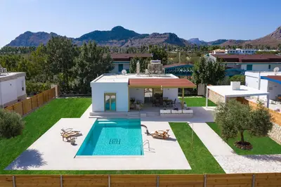 a backyard with a swimming pool and a house at Serenity Villas in Kolimbia