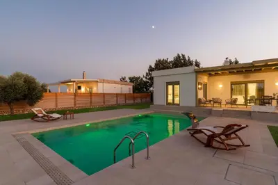a swimming pool in front of a house at Serenity Villas in Kolimbia