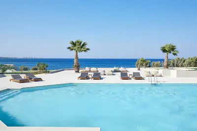 a swimming pool with chairs and palm trees and the ocean at Ella Elissa - Adults Only in Kallithea Rhodes